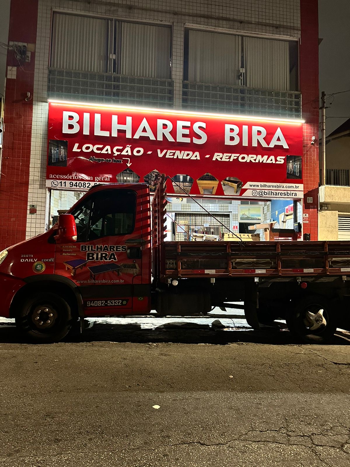 Fachada vermelha da loja Diversões Bira com caminhão de entrega estacionado à frente