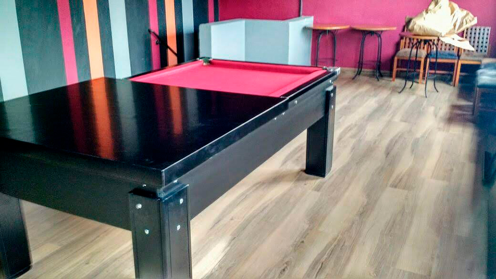 Mesa de bilhar residencial preta com tampo jantar e pano vermelho em sala de jogos