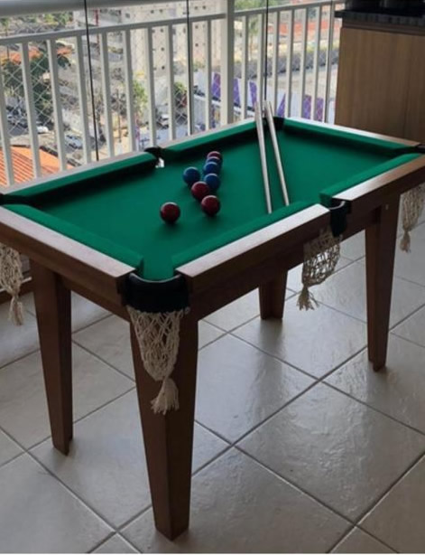 Mesa de bilhar infantil de madeira com pano verde e redinhas, instalada em varanda