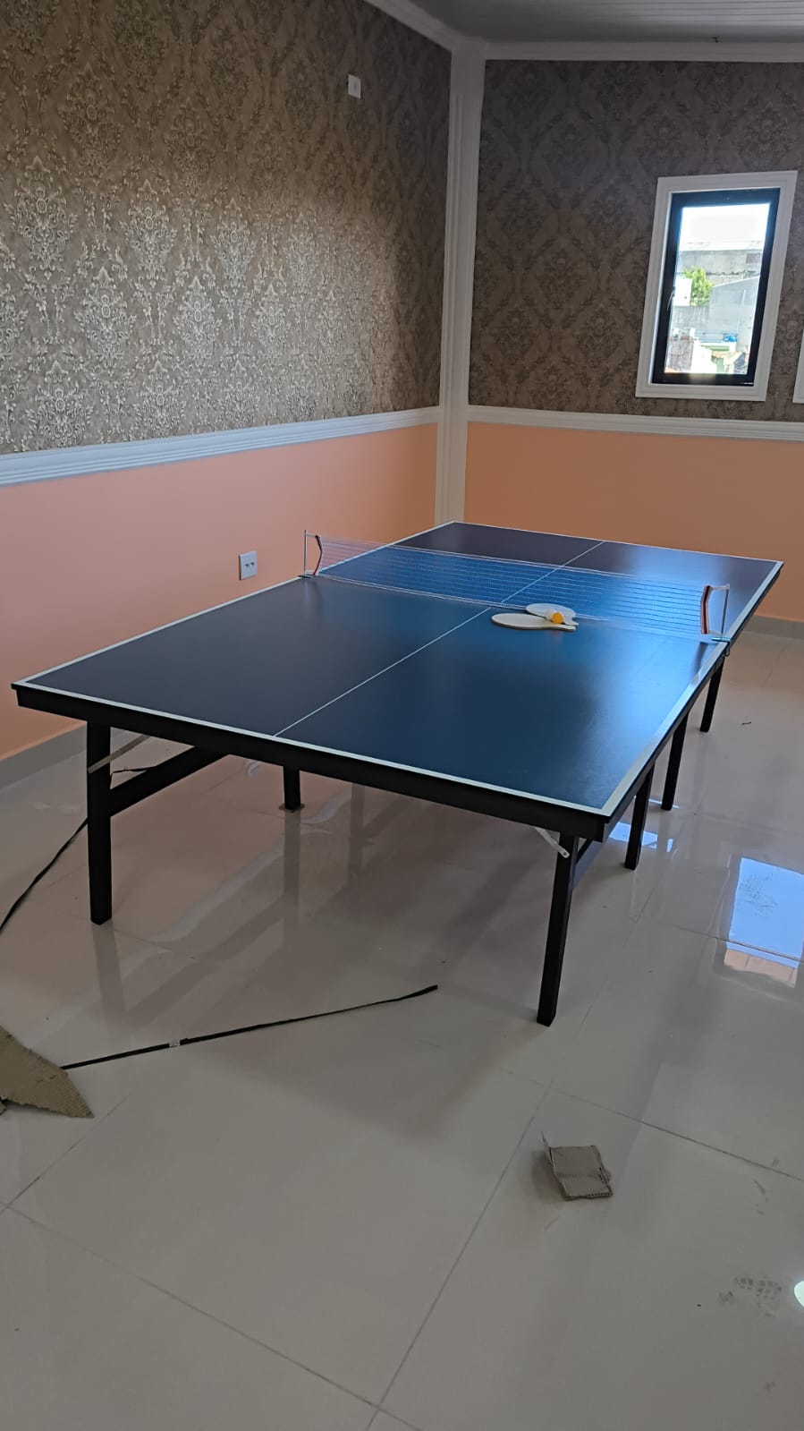 Mesa de ping pong montada em sala de jogos residencial