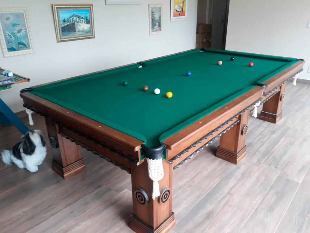Mesa de bilhar profissional com pano verde instalada em sala residencial